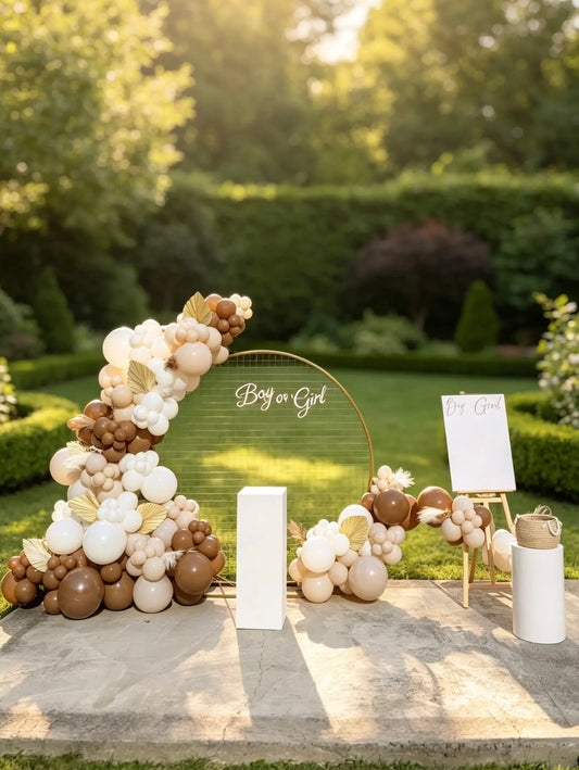Neutral gender reveal setup with gold mesh backdrop, beige, brown and white balloon garland, Boy or Girl sign and voting station.