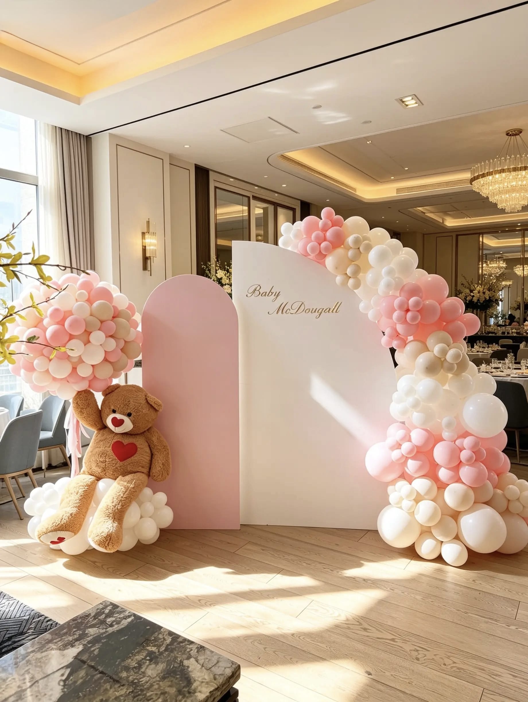 Pink teddy bear baby shower backdrop with layered blush and white backdrops, an organic balloon garland and an oversized teddy bear.