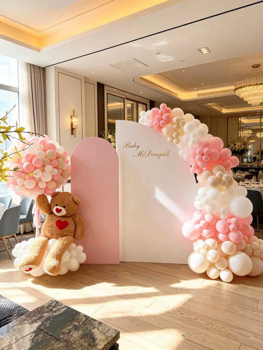 Pink teddy bear baby shower backdrop with layered blush and white backdrops, an organic balloon garland and an oversized teddy bear.