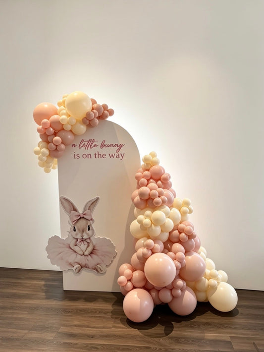 pink bunny baby shower backdrop with pastel balloon garlands and bunny cutout