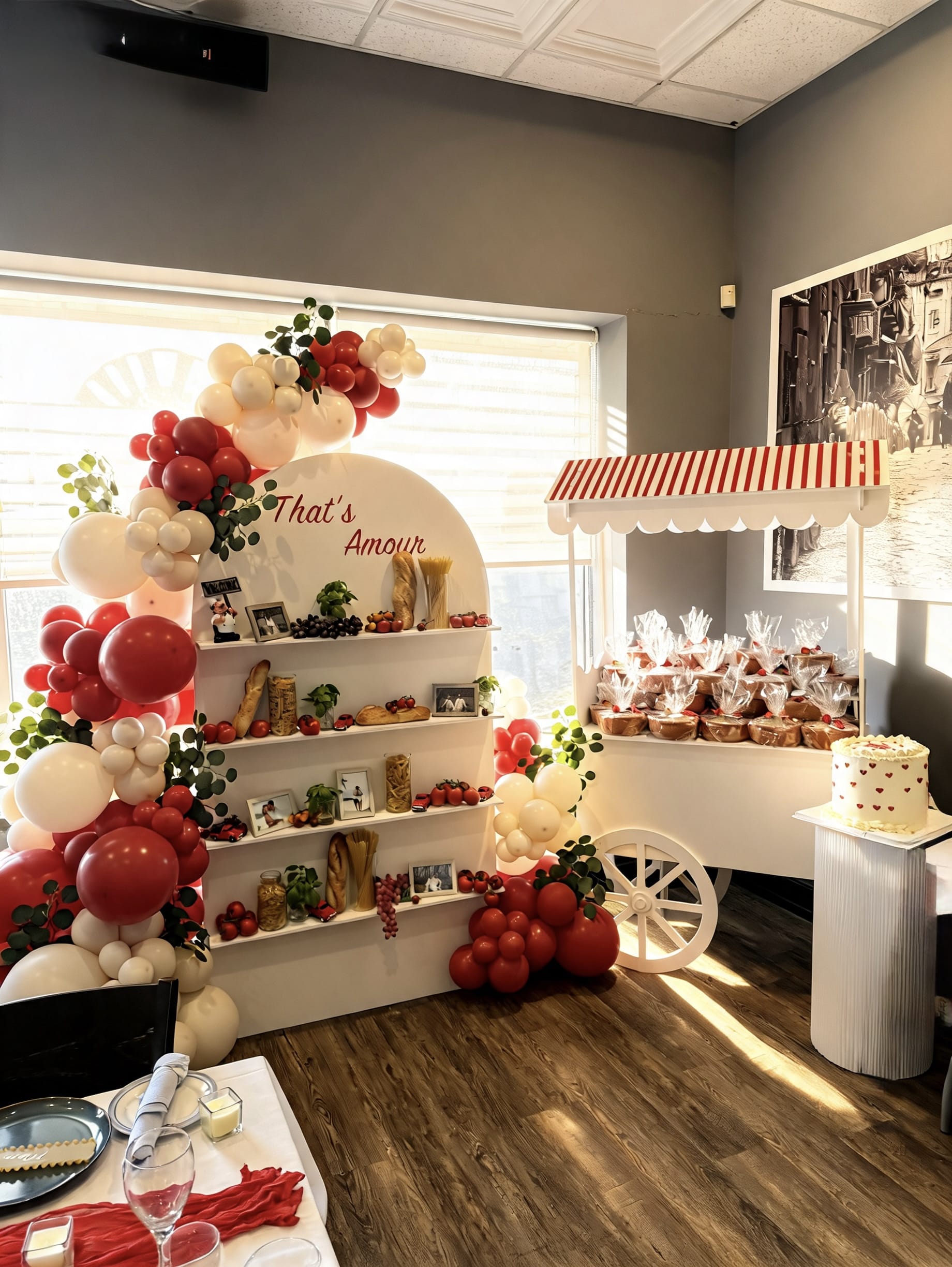 Italian market themed party display with red and white balloon garland, custom shelving, market cart and romantic celebration décor.