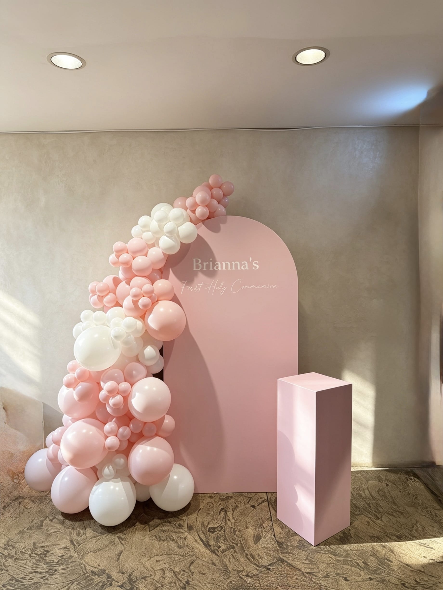 Blush pink communion backdrop with white and pink organic balloon garland and matching pedestal stand