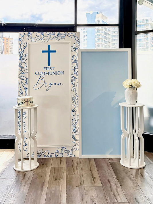 Blue and white first communion backdrop with floral frame design, custom name and matching pedestal stands.