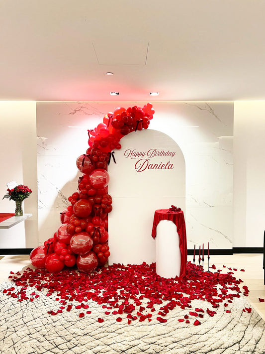 luxury red birthday balloon backdrop with velvet table and rose petals
