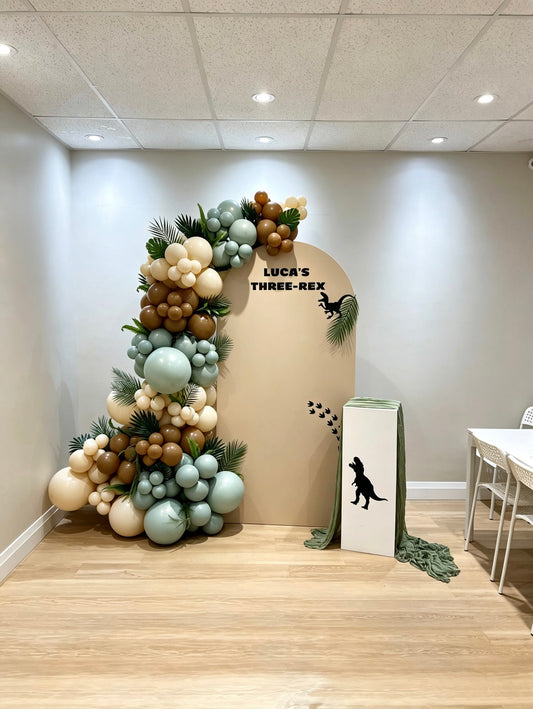 dinosaur birthday balloon backdrop with green garland and jungle decor
