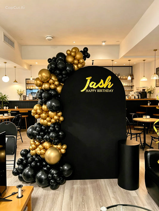 black and gold birthday balloon backdrop with black cake table
