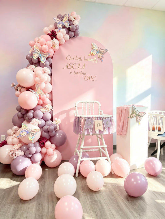 pink butterfly first birthday backdrop with pastel balloon garland and styled high chair