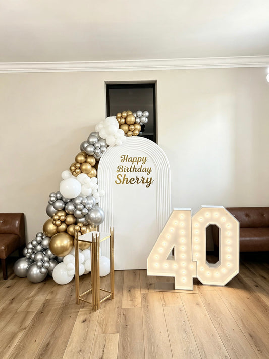 White ripple arch birthday backdrop with white gold and silver balloon garland and marquee 40 numbers