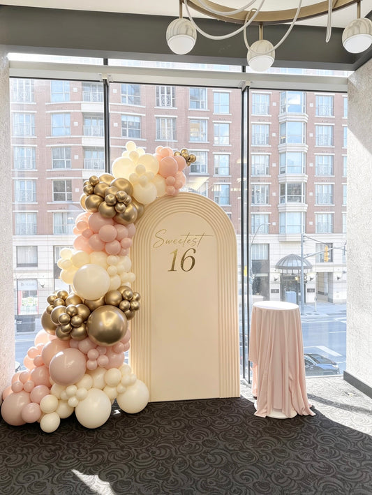 white ripple arch sweet 16 backdrop with blush pink ivory and gold balloon garland