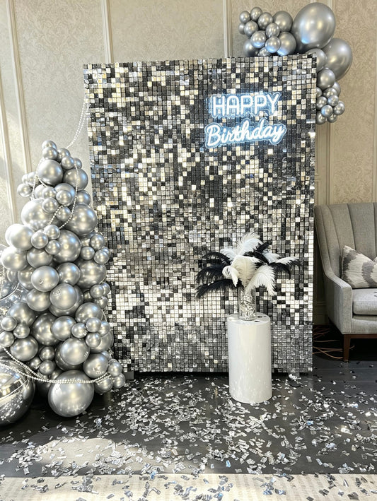 silver shimmer wall backdrop with chrome silver balloons and neon happy birthday sign