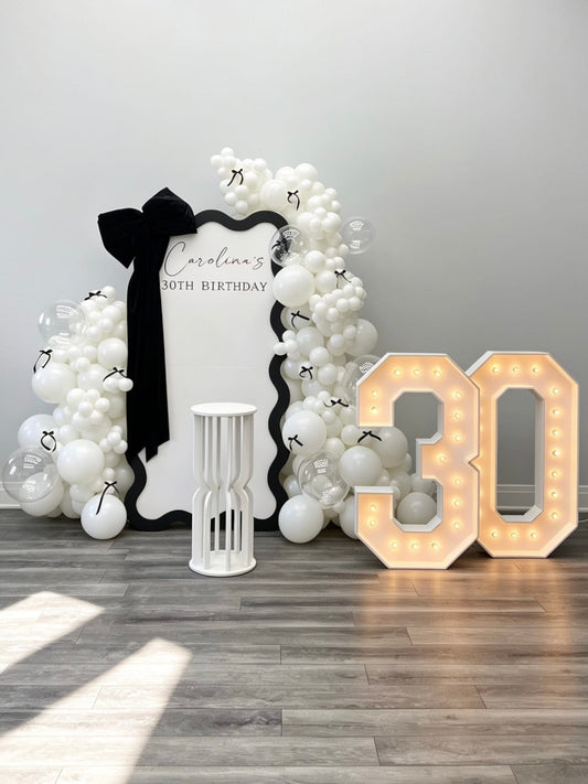 modern black and white birthday backdrop with oversized bow and marquee numbers