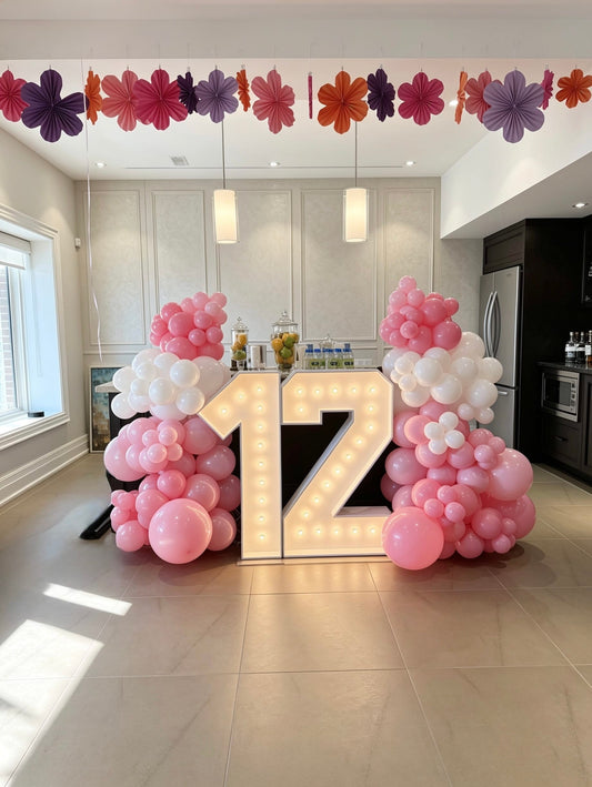 Pink and white balloon garlands with illuminated marquee number 12 setup
