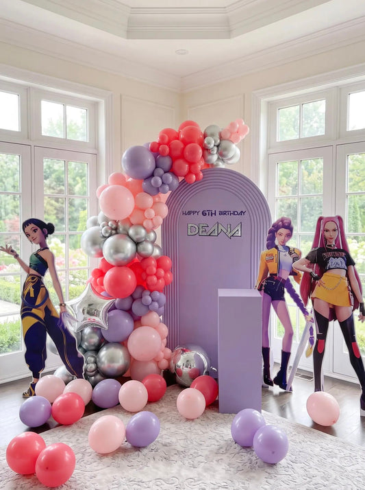 KPop Demon Hunters birthday backdrop with a lavender ripple arch, pink, coral, purple and silver balloon garland, themed character cutouts and custom birthday lettering.