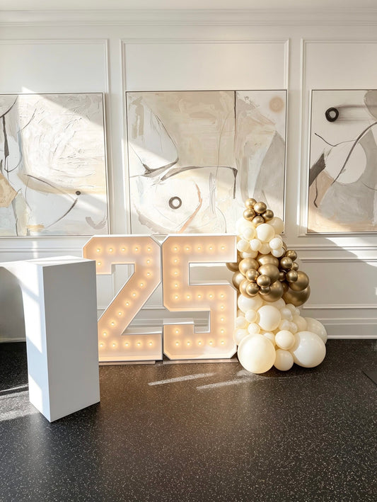 light up marquee numbers with white and gold balloon garland and cake table