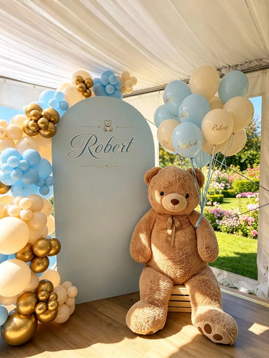 Teddy bear christening backdrop with baby blue, ivory and gold balloon garland, personalized name sign and custom helium balloons.