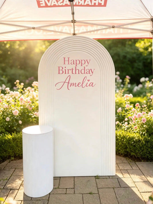 White ripple arch birthday backdrop with custom Happy Birthday sign and matching white ribbed pedestal