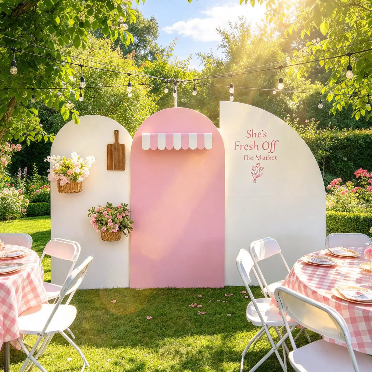 Pink and cream bridal shower backdrop with a striped awning, hanging flower baskets, and “She’s Fresh Off the Market” lettering.