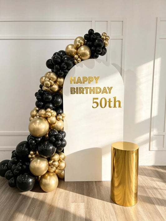 classic black and gold birthday backdrop with luxury balloon garland and gold pedestal