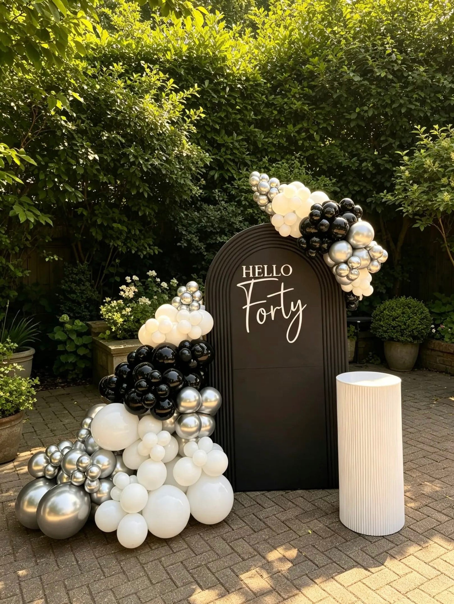  Black 40th birthday backdrop with Hello Forty sign, black, white and metallic silver balloon garland, and white ripple cake table.