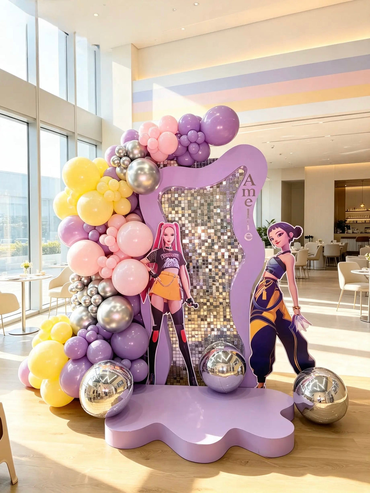 K-Pop Demon Hunters birthday setup with a purple wavy frame, silver shimmer wall, pastel balloons, two character cutouts, and a purple platform.