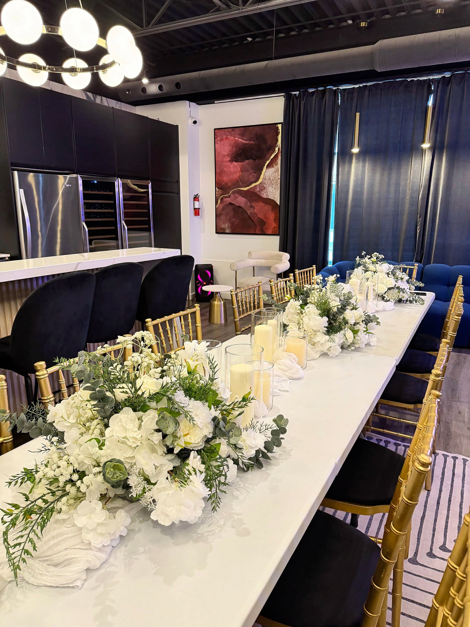 Elegant 12 ft table styling with white floral centerpieces, candles in glass vases and layered table runners