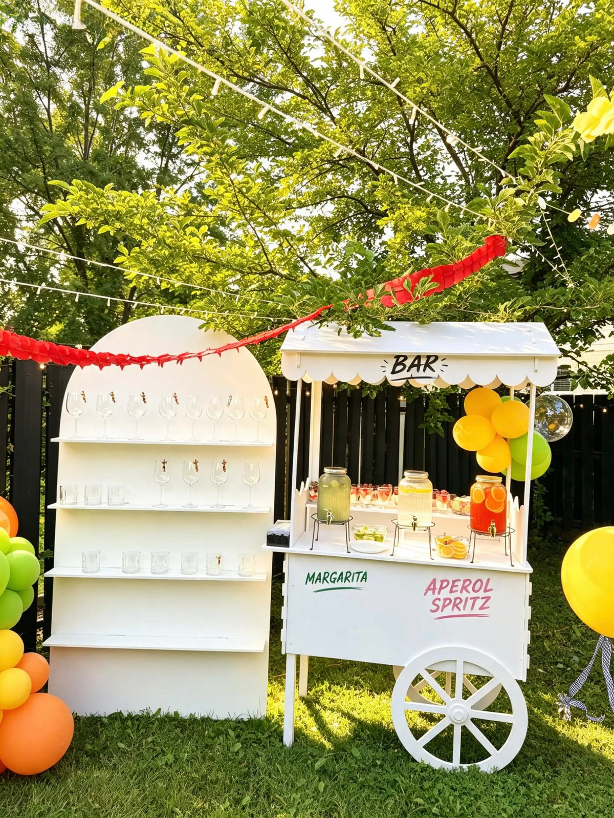 White cocktail bar cart with a scalloped canopy, Margarita and Aperol Spritz lettering, and a matching arched glassware display outdoors.