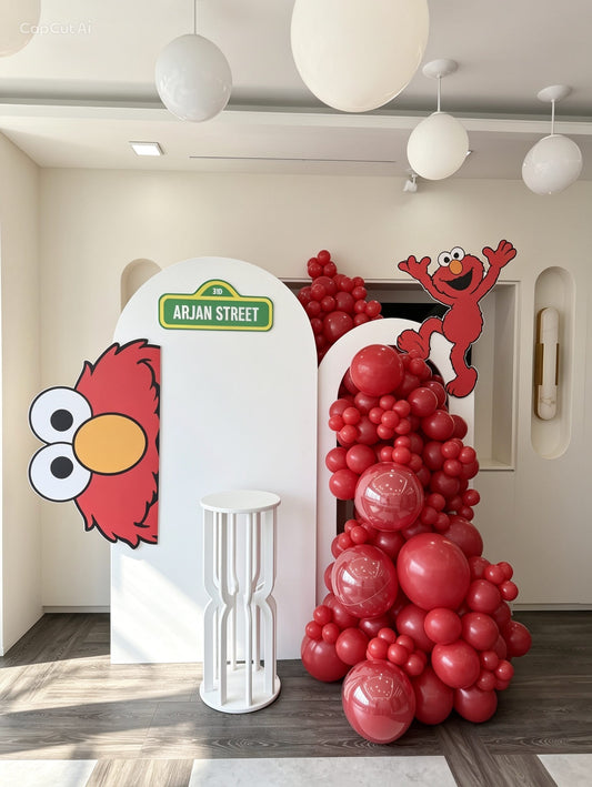 Elmo birthday backdrop with red balloon garland and Sesame Street themed cutouts