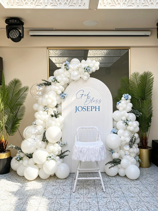 white baptism backdrop with ripple arch and elegant balloon garlands