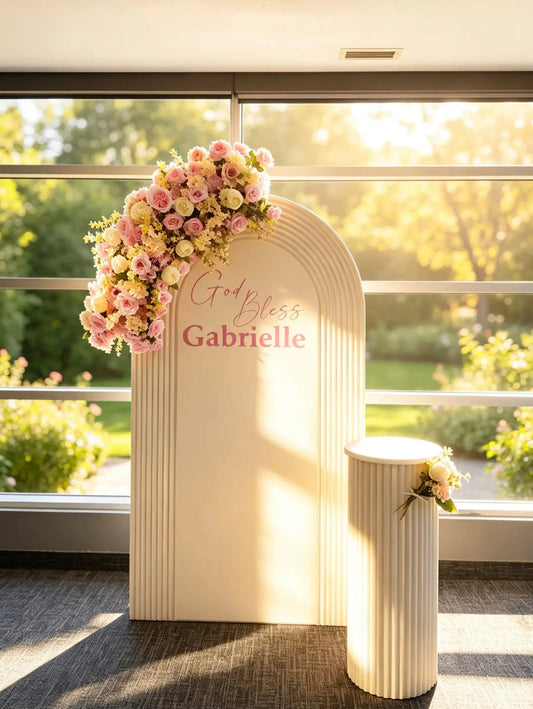 Ivory christening backdrop with God Bless personalized name, cascading pink and ivory flowers and matching ribbed cake table.