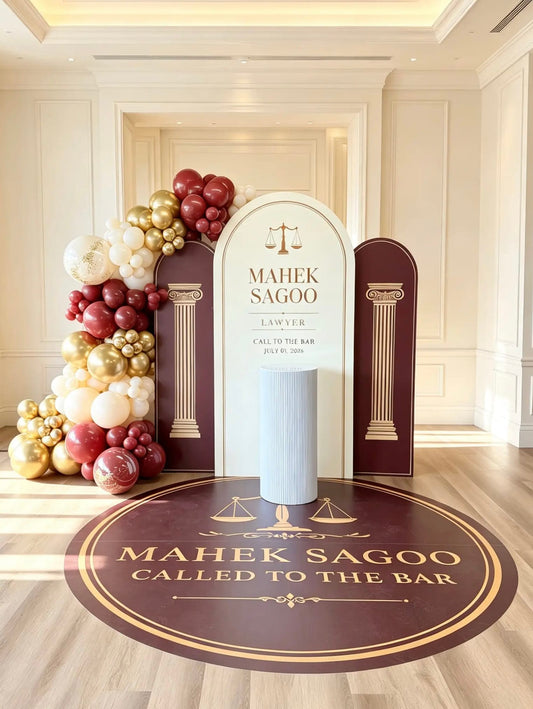 Called to the Bar celebration backdrop with burgundy, ivory and gold balloons, personalized law-themed panels, floor graphic and cake table.