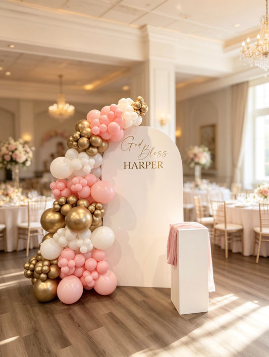 White communion backdrop with pink, white and gold balloon garland and matching pedestal stand