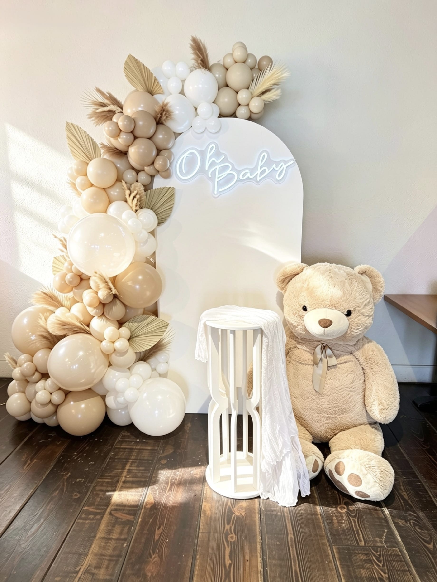 soft ivory baby shower backdrop with neutral balloon garland and teddy bear
