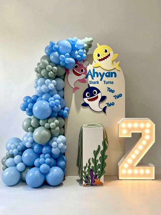 baby shark birthday backdrop with blue balloon garland and marquee number