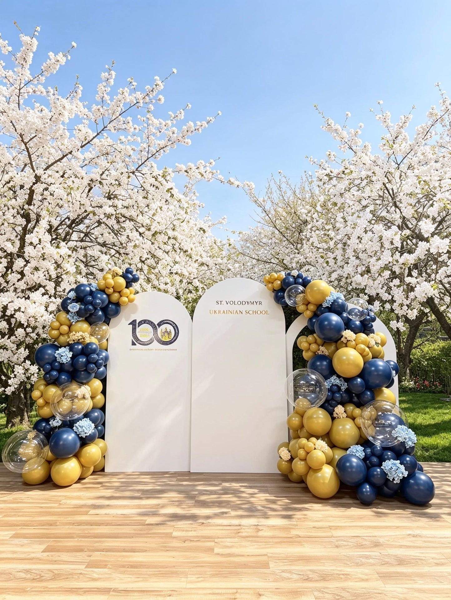 Three-panel church centennial backdrop with blue and gold balloon garlands, faux floral accents, clear bubble balloons, and custom signage for a 100th anniversary celebration.