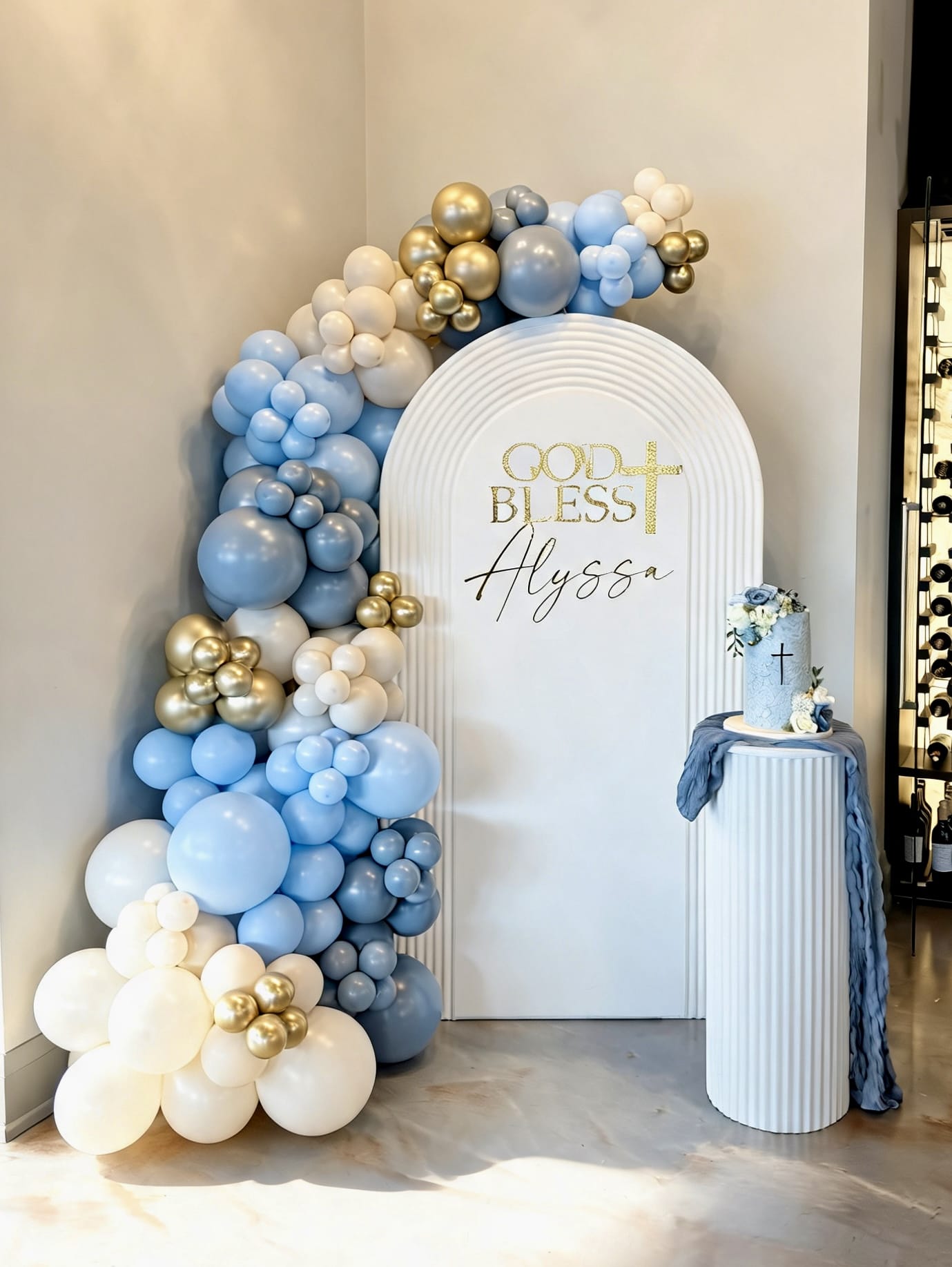 White ripple arch backdrop with blue, ivory and gold balloon garland for a First Holy Communion celebration.