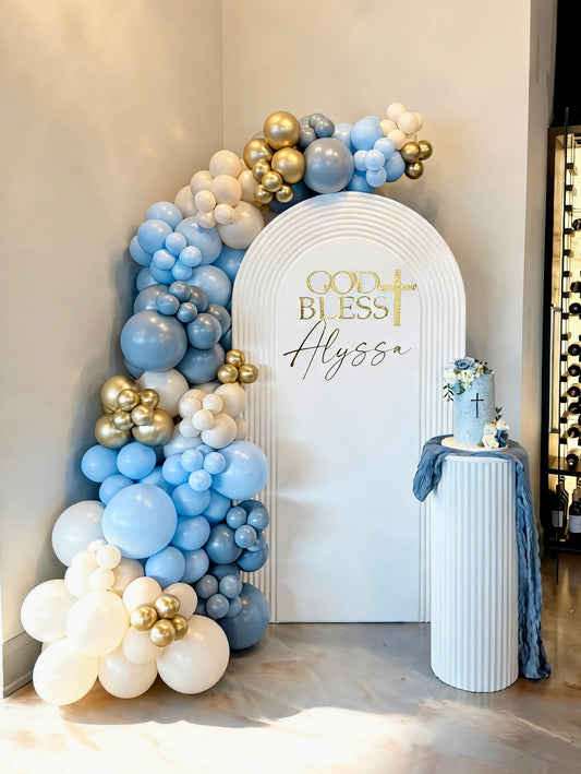 White ripple arch backdrop with blue, ivory and gold balloon garland for a First Holy Communion celebration.