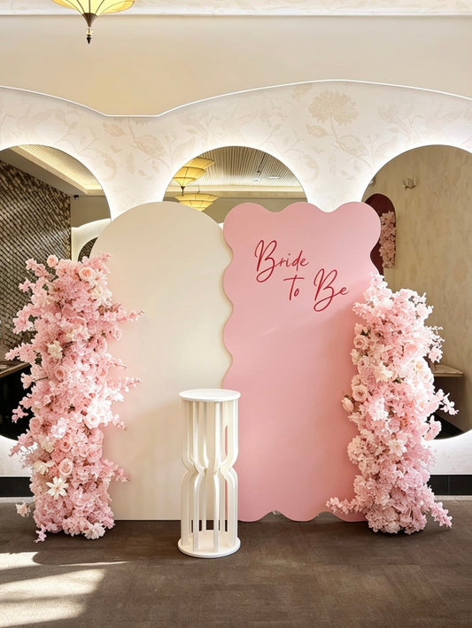 Blush pink bridal shower backdrop with layered panels and floral columns.